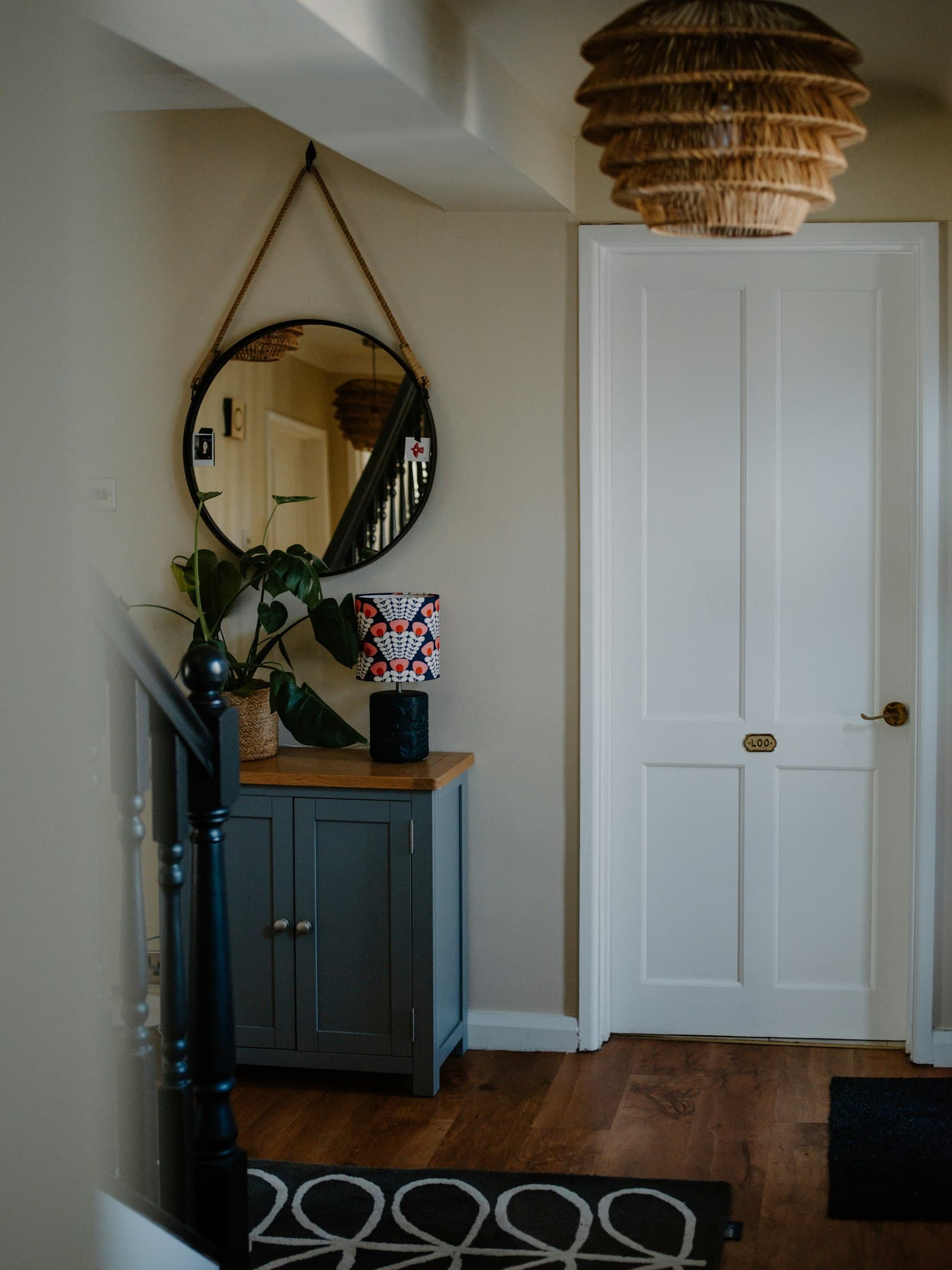 A hallway with a round mirror above a low cabinet